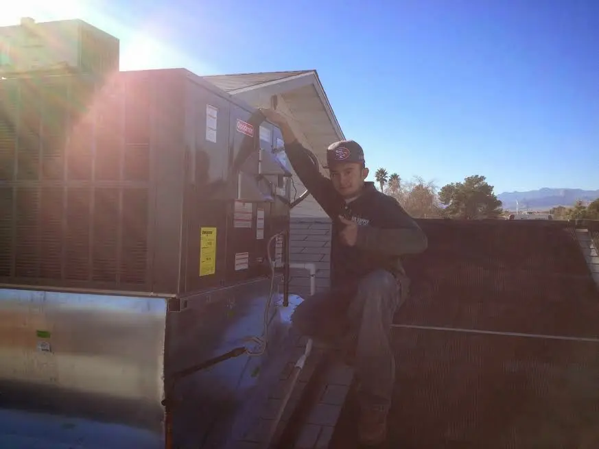 HVAC technician performing AC Tune-Up on a rooftop unit in Tomah